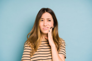 Woman rubbing her swollen face and looking concerned